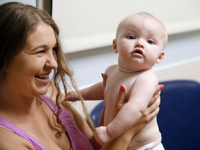 In this July 13, 2017 photo, Stephanie Gaffney bounces her daughter, Elliana, when she was 8 months old and visiting the neonatal-abstinence syndrome clinic at Cincinnati Children's Hospital Medical Center. The Cincinnati Enquirer is donating $5,000 of its 2018 Pulitzer Prize for local reporting to benefit Elliana featured in the newspaper's winning report on heroin. Gaffney died of an overdose of a fentanyl combination 10 days after speaking with the newspaper for the story.