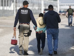 Government agents take a woman suspected of living in the country illegally into custody during an immigration sting at Corso's Flower and Garden Center in Castalia, Ohio, Tuesday, June 5, 2018. The operation is one of the largest against employers in recent years on allegations of violating immigration laws.
