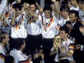 FILE - in this  July 8, 1990 file photo, Germany's soccer captain Lothar Matthaus kisses the World Cup trophy after his team beat Argentina in the final 1-0 in the Olympic Stadium, in Rome, Italy. Coach Franz Beckenbauer, in dark jacket, stands behind Matthaus. The 21st World Cup begins on Thursday, June 14, 2018, when host Russia takes on Saudi Arabia.