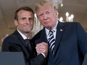 FILE - In this Tuesday, April 24, 2018 file picture President Donald Trump and French President Emmanuel Macron embrace at the conclusion of a news conference in the East Room of the White House in Washington. Tensions are mounting between French President Emmanuel Macron and U.S. President Donald Trump, meeting Friday with other leaders at the G-7 summit in Canada. Just six weeks ago Macron and Trump exhibited their friendship at a state dinner in Washington but today Macron is positioning himself to lead the anti-Trump brigade at the G7.