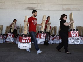 FILE - In this June 1, 2018, file photo, members of the the Culinary Union carry signs at a union hall in Las Vegas. Unionized workers at the casino-resorts operated by Caesars Entertainment in Las Vegas are casting ballots Thursday, June 14 to ratify their newly negotiated five-year contract.