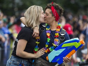 Two women share a kiss at the 2018 Toronto Pride Parade on the corner of Yonge and Bloor Streets, in Toronto, Ont.  on Sunday June 24, 2018.