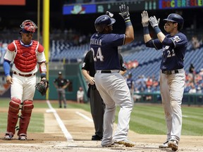 Milwaukee Brewers' Jesus Aguilar, center, celebrates with Christian Yelich, right, after Aguilar's two-run home run during the first inning of a baseball game against the Philadelphia Phillies, Saturday, June 9, 2018, in Philadelphia. At left is catcher Jorge Alfaro.