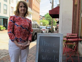 Mary Adams, owner of The Annapolis Bookstore, stands by a sign outside her store on Saturday, June 30, 2018 in downtown Annapolis, Md. Adams, who knew two of the journalists who were killed in the attack on The Capital newspaper, said the shooting has made the entire community very sad.