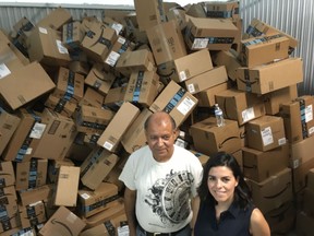 In this photograph taken June 24, 2018, Catholic Charities of the Rio Grande Valley staffer Eli Fernandez and volunteer Natalie Montelongo pose for a photo as they stand by a pile of unsorted Amazon boxes packed with donations in McAllen, Texas. A rest center for asylum-seekers in the Texas border town of McAllen has seen such a big surge of donations that they've had to rent additional storage space, and caravans of volunteers from across the U.S. have also showed up at their doors.