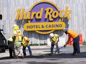 In this June 18, 2018 photo workers rake asphalt outside the Hard Rock casino in Atlantic City, N.J. With the former Revel due to reopen as the Ocean Resort Casino, and the former Trump Taj Mahal due to reopen as the Hard Rock - both on the same day, June 28 - crews are scrambling to get both properties ready for their grand openings.