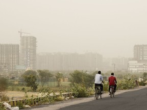 Cyclists pedal on a road enveloped by a thick haze of dust in Greater Noida, on the outskirts of New Delhi, India, Thursday, June 14, 2018. The Indian capital region experienced severe levels of pollution for the third straight day on Thursday. Over the past two years, New Delhi has earned the dubious distinction of being one of the world's most polluted cities.