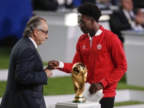Decio de Maria, President of the Football Association of Mexico, left, and Canadian soccer player Alphonso Davies, right, present a joint United bid by Canada, Mexico and the United States to host the 2026 World Cup at the FIFA congress in Moscow on June 13.