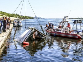 In this Russian Emergency Situations Ministry photo, made available on Tuesday, June 12, 2018, emergency situations employees attend the scene of an overturned boat after a collision on the Volga River in Volgograd, southern Russia.