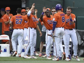 Clemson's Chris Williams (27), left, and Logan Davidson (8) are congratulated by teammates after scoring on a double by Kyle Wilkie during an NCAA college baseball regional game against St. John's, Sunday, June 3, 2018, in Clemson, S.C.