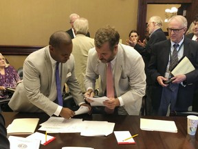 House Minority Leader Todd Rutherford, left, and state Rep. Kirkman Finlay, right, sign a compromise proposal that would temporarily lower electric rates for South Carolina Electric & gas customers 15 percent on Wednesday, June 27, 2018, in Columbia, SC. The House and Senate will consider the bill which nearly eliminates rate increases used to pay for two nuclear reactors that were never built.