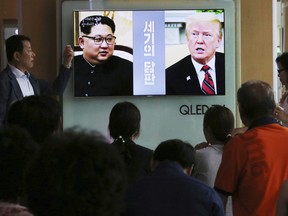 People watch a TV screen showing file footage of U.S. President Donald Trump, right, and North Korean leader Kim Jong Un during a news program at the Seoul Railway Station in Seoul, South Korea, Tuesday, June 5, 2018. The White House says Trump's meeting with Kim is set for 9 a.m. on June 12 in Singapore, which is 9 p.m. on June 11 on the U.S. East Coast. The signs read: " Negotiations of the century."