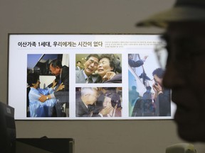 Photos showing the reunion of family members from North and South Korea are displayed as South Korean Yoo Gi-jin, 93, talks with a Red Cross official to fill out application forms to reunite with his family members living in North Korea, at the headquarters of the Korea Red Cross in Seoul, South Korea, Friday, June 22, 2018. North and South Korean officials met Friday for talks on resuming reunions of families divided by the 1950-53 Korean War as the rivals boost reconciliation amid a diplomatic push to resolve the North Korean nuclear crisis. The signs on the photos read: "1st generation of separated families. We do not have time."