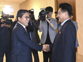 In this photo provided by the South Korea Culture And Sports Ministry, North Korean head delegate Won Kil U, right, shakes hands with his South Korean counterpart Jeon Choong-ryul as he arrives to hold a meeting at the southern side of Panmunjom in the Demilitarized Zone, North Korea, Monday, June 18, 2018. Sports officials from the rival Koreas are meeting at a border village to discuss how to cooperate in the Asian Games being held in Indonesia in August. (South Korea Culture And Sports Ministry via AP)