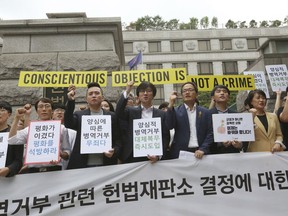 Activists for conscientious objectors stage a rally demanding the government to work out alternatives in front of the Constitutional Court in Seoul, South Korea, Thursday, June 28, 2018. South Korea's Constitutional Court has ruled that the country must allow alternative social service for people who conscientiously object to military service, which is currently mandatory for able-bodied males. The signs read: " We call for the government to work out alternatives."