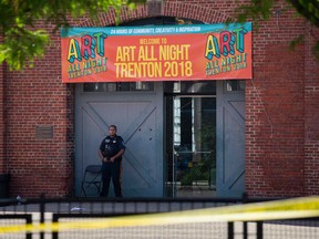 A Police officer stands in front as other officers inspect the crime scene at the Roebling Market on June 17, 2018, the morning after a shooting at an all-night art festival injured 20 people and left one suspect dead in Trenton, New Jersey.