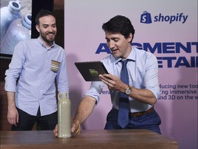 Prime Minister Justin Trudeau uses Shopify's augmented reality technology as Shopify's Daniel Beauchamp, left, looks on in Toronto on Tuesday, May 8, 2018.