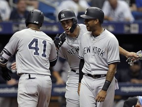 New York Yankees' Miguel Andujar, left, celebrates with Giancarlo Stanton, center, and Aaron Hicks, right, after hitting a three-run home run off Tampa Bay Rays pitcher Matt Andriese during the second inning of a baseball game Sunday, June 24, 2018, in St. Petersburg, Fla.
