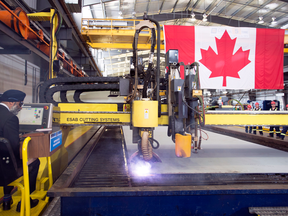 Defence Minister Harjit Sajjan, left, cuts steel for the first of two Joint Support Ships for Canada's Navy at the Seaspan Shipyards in Vancouver, June, 15, 2018.