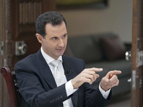 In this file photo released May 10, 2018, by the Syrian official news agency SANA, Syrian President Bashar Assad speaks during an interview with the Greek Kathimerini newspaper, in Damascus, Syria.
