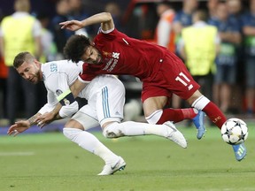 FILE - In this Saturday, May 26, 2018 file photo Real Madrid's Sergio Ramos, left, fouls Liverpool's Mohamed Salah during the Champions League Final soccer match between Real Madrid and Liverpool at the Olimpiyskiy Stadium in Kiev, Ukraine. Sergio Ramos isn't taking blame for the challenge that ended hurting Egypt star Mohamed Salah in the Champions League final. Salah left the field in tears after injuring his left shoulder in a tussle with Ramos with the score 0-0 in the first half.