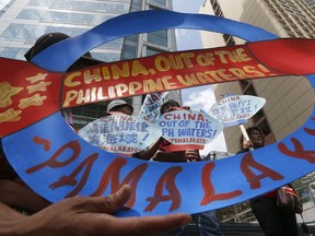 FILE - In this May 18, 2018, file photo, protesters display placards during a rally at the Chinese Consulate to protest China's deployment of missiles on the Philippine-claimed reefs in South China Sea in the financial district of Makati city east of Manila, Philippines. Filipino officials say China's coast guard has continued to seize the catches of Filipino fishermen at a disputed shoal.