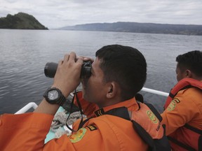 FILE - In this June, 20, 2018, file photo, Indonesian rescuers scan the horizon from the deck of a rescue ship as they search for a ferry which sank in Lake Toba, North Sumatra, Indonesia. Indonesia has identified the suspected location of an overcrowded ferry that sank last week in a deep volcanic crater lake but will need international help to recover the wreck, the chief of the national search and rescue agency said Monday, June 25, 2018.