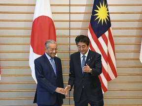 Malaysian Prime Minister Mahathir Mohamad, left, is shown the way by his Japanese counterpart Shinzo Abe, prior to their talks at Abe's official residence in Tokyo Tuesday, June 12, 2018.