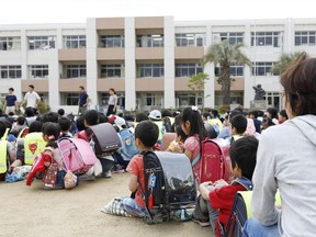 School children take shelter at schoolyard in Ikeda, Osaka, following an earthquake Monday, June 18, 2018.  A strong earthquake has shaken the city of Osaka in western Japan. There are reports of scattered damage including broken glass and concrete.