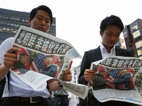 People look at the extra edition of  Japanese newspaper Mainichi Shimbun reporting the summit between U.S. President Donald Trump and North Korean leader Kim Jong Un in Singapore, at Shimbashi Station in Tokyo, Tuesday, June 12, 2018.  The headline reads: North Korea promises to denuclearize.