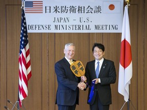 U.S. Defense Secretary Jim Mattis, left, and Japanese Defense Minister Itsunori Onodera, pose with "gunbai," sumo referee's fan, for a photo before their meeting at Defense Ministry in Tokyo Friday, June 29, 2018. The fan reads: "World peace."