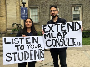 University of Toronto students Kira Patel, 21, and Moaz Shoura, 21, hold signs during a protest on campus in Toronto on Wednesday, June 27, 2018 as the university decides whether or not to implement a policy that could place students with mental health issues on a mandatory leave of absence if the school deems it necessary.