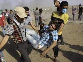 Palestinian medics and protesters evacuate a wounded youth near the Gaza Strip's border with Israel, during a protest east of Khan Younis, in the Gaza Strip, Friday, June 8, 2018. About 300 university academics from around the country have signed an open letter calling on Prime Minister Justin Trudeau to keep his word and ensure there is an independent investigation into the Israeli army's use of force against Palestinians in Gaza.
