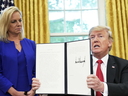 As Homeland Security Secretary Kirstjen Nielsen watches, President Donald Trump holds up an executive order he signed to end family separations at the border, June 20, 2018.