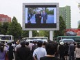 People watch a large screen at the main train station airing video of North Korean leader Kim Jong Un shaking hands with Singapore Prime Minister Lee Hsien Loong during his trip to Singapore in Pyongyang, North Korea, Monday, June 11, 2018.