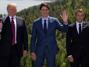 (L-R) US President Donald Trump, Canadian Prime Minister Justin Trudeau and French President Emmanuel Macron wave during the family photo at the G7 Summit in La Malbaie, Canada, June 8, 2018.