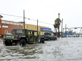 A military all-terrain vehicle pushes into floodwaters Wednesday, June 20, 2018, on Texas Avenue in Weslaco, Texas. Heavy rains along the Texas coast have caused flooding in areas that were hit hard by Hurricane Harvey less than a year ago.