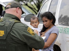 A mother migrating from Honduras holds her one-year-old child while surrendering to U.S. Border Patrol agents after illegally crossing the border on June 25, 2018, near McAllen, Texas.