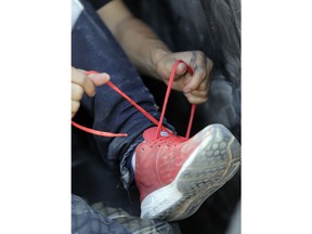 A migrant trying to illegally enter the United States removes his shoe laces after being caught by U.S. Border Patrol agents, Monday, June 25, 2018, in Hidalgo, Texas.