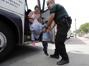 A transport officer, right, helps immigrants Dilma Araceley Riveria Hernandez, and her son, Anderson Alvarado, 2, get off the bus after they were processed and released by U.S. Customs and Border Protection, Sunday, June 24, 2018, in McAllen, Texas.