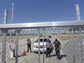 Department of Homeland Security and Customs and Border Patrol agents stand behind a closed gate at the Port of Entry facility, where tent shelters are being used to house separated family members, Thursday, June 21, 2018, in Fabens, Texas. President Donald Trump on Wednesday signed an order to stop the separations. Justice Department lawyers are working on a legal challenge to allow families to be detained longer than 20 days.