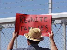 A protester holds a sign outside a closed gate at the Port of Entry facility, Thursday, June 21, 2018, in Fabens, Texas, where tent shelters are being used to house separated family members. President Donald Trump's order ending the policy of separating immigrant families at the border leaves a host of unanswered questions, including what happens to the more than 2,300 children already taken from their parents and where the government will house all the newly detained migrants in a system already bursting at the seams.
