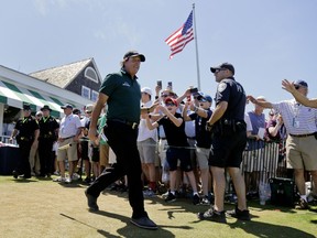 Phil Mickelson greets fans as he arrives for the third round of the U.S. Open Golf Championship, Saturday, June 16, 2018, in Southampton, N.Y.