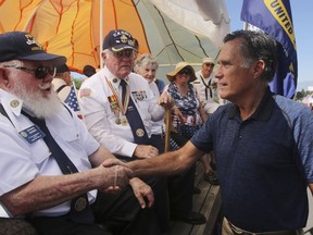 In this Saturday, June 23, 2018, photo, Mitt Romney shakes hands during the Strawberry Day Parade in Pleasant Grove, Utah. Romney faces state lawmaker Mike Kennedy on Tuesday, June 26, 2018, as the ex-presidential nominee looks to restart his political career with the Utah's open U.S. Senate seat. Romney is competing with Kennedy in a primary election to replace U.S. Sen. Orrin Hatch, who is retiring after more than 40 years in office.