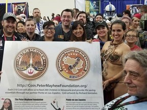 This May 29, 2018 photo provided by Elisa Arguello shows actor Peter Mayhew, front right, posing for a photo with members of the "Star Garrison," the Texas chapter of Star Wars Fan Club "501st Legion," including Venezuelan Elisa Arguello, dressed as Princes Leia, as they launch the Chewbacca Challenge Coin, a fundraising campaign whose proceeds will benefit a charity feeding underprivileged children in Venezuela, during the Comicpalooza event in Houston Texas. The copper coins are being sold online for $10 by the Peter Mayhew foundation. But proceeds will go to "Ponte en sus zapatos, a small Texas charity that has been working in Venezuela for over a year and claims to feed 100 needy children every day. (Elisa Arguello via AP)