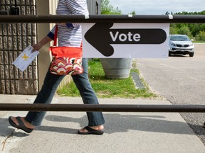 A woman walks past a sign that says 'vote' to a ballot station to vote in the 2018 Ontario election on Thursday, June 7, 2018.