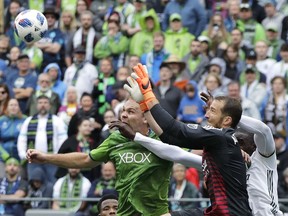 Portland Timbers goalkeeper Jeff Attinella, second from right, leaps to grab the ball in front of Timbers' Larrys Mabiala, right, and Seattle Sounders defender Chad Marshall, left, in the second half of an MLS soccer match, Saturday, June 30, 2018, in Seattle. The Timbers won 3-2.
