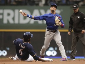 Milwaukee Brewers' Lorenzo Cain is out at second as Chicago Cubs' Javier Baez turns a double play on a ball hit by Christian Yelich during the first inning of a baseball game Monday, June 11, 2018, in Milwaukee.