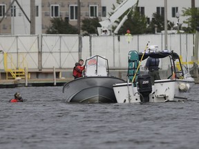 Members of the Winnebago County Sheriff's Department dive team search the Fox River in Oshkosh, Wis., on Saturday, June 9, 2018 where a helicopter crashed. Witness Gary Lemiesz said the aircraft struck the wires and part of the propeller broke off, after which "it hit hard and sunk."