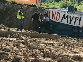 In this Monday, June 4, 2018 photo, a protester is arrested at a Mountain Valley Pipeline worksite near Lindside, W.Va. Three protesters from Massachusetts were arrested after binding themselves to equipment at the site in West Virginia to halt the construction of the Mountain Valley Pipeline.